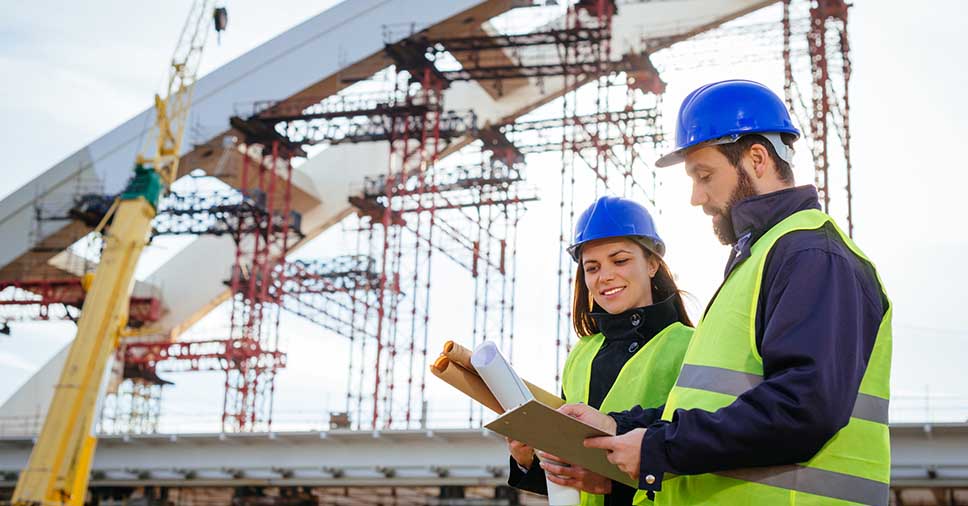 Dois engenheiros de uma empresa de construção civil trabalhando no canteiro de obras